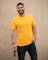 man in yellow crew neck t-shirt and black denim jeans standing beside white wall