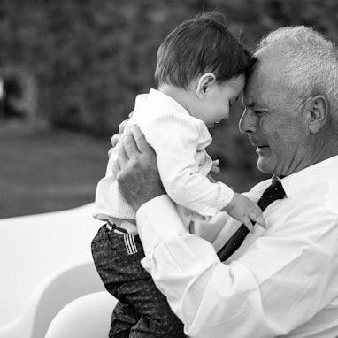 man in white dress shirt carrying baby in black and white long sleeve shirt