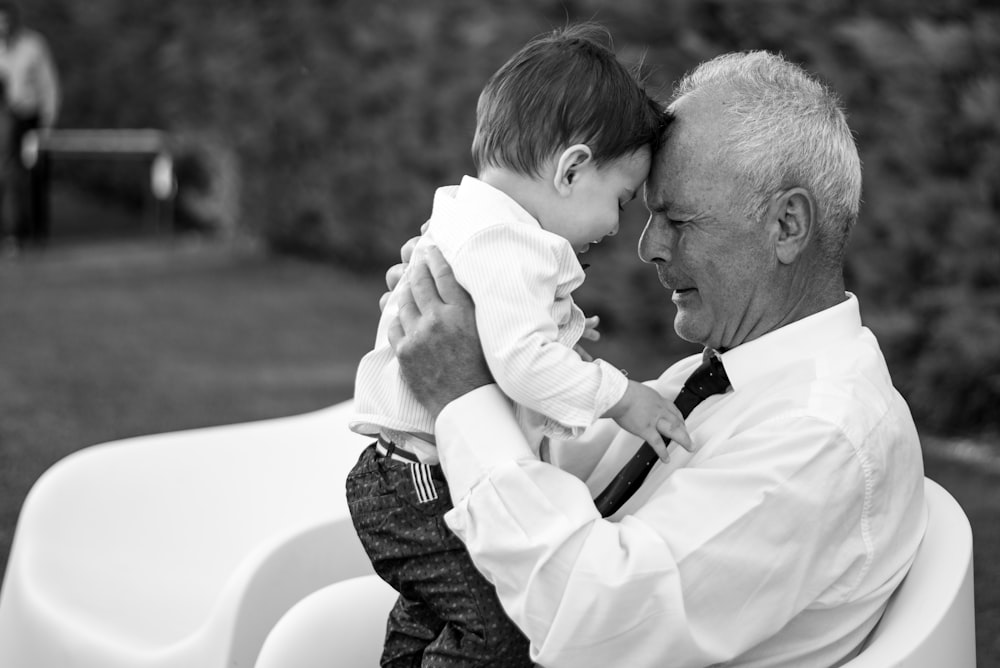 man in white dress shirt carrying baby in black and white long sleeve shirt