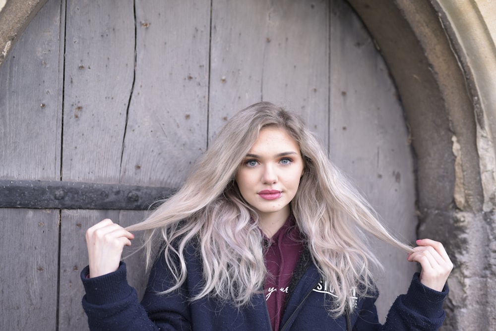 woman in black jacket standing beside brown wooden wall