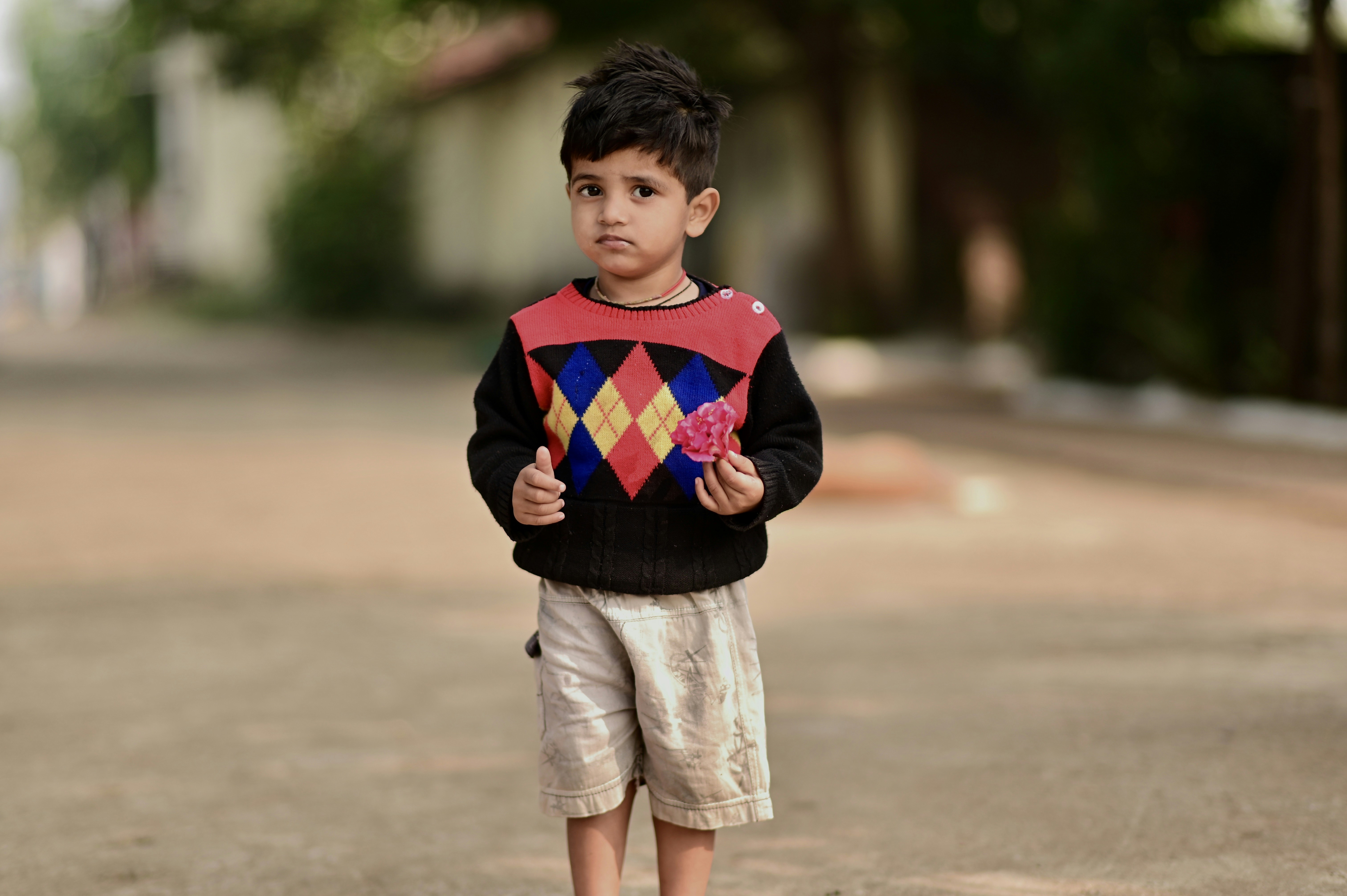 boy in blue red and green striped long sleeve shirt standing on road during daytime