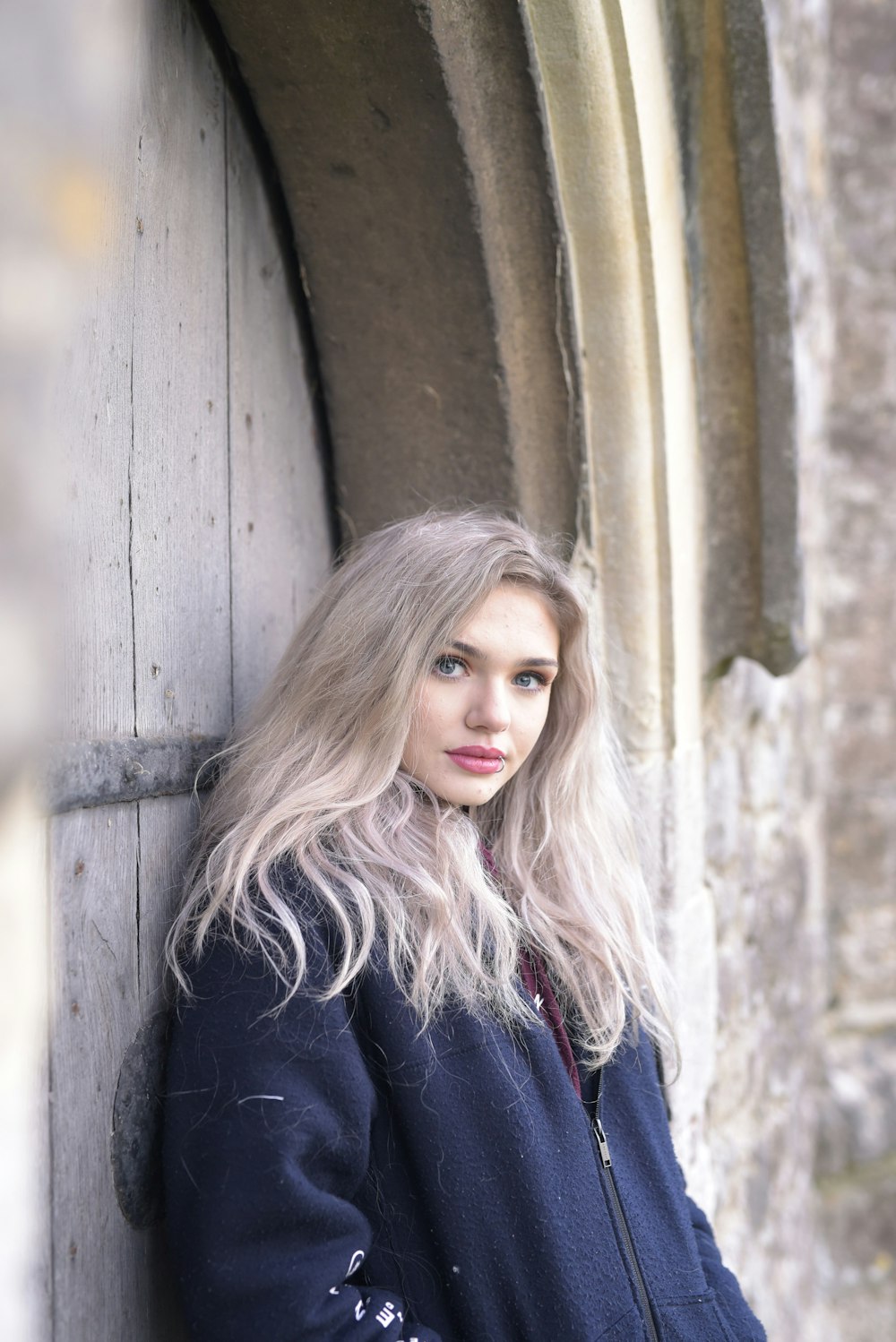 woman in black jacket standing beside brown wooden wall during daytime