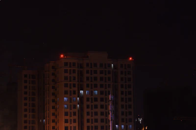 Night view of a luxury building illuminated with soft red lighting highlighting its architecture.