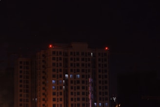 Nighttime exterior of a residential tower illuminated by soft, ambient lighting.