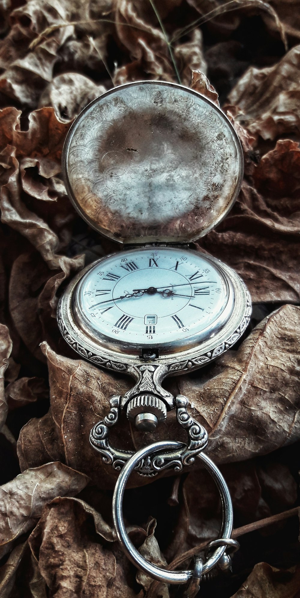 silver pocket watch on brown textile