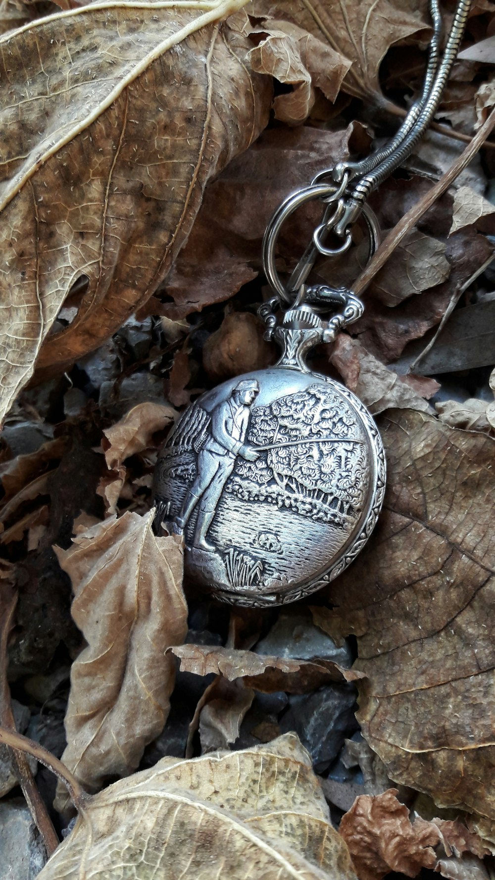 orologio da tasca rotondo in argento su foglie secche
