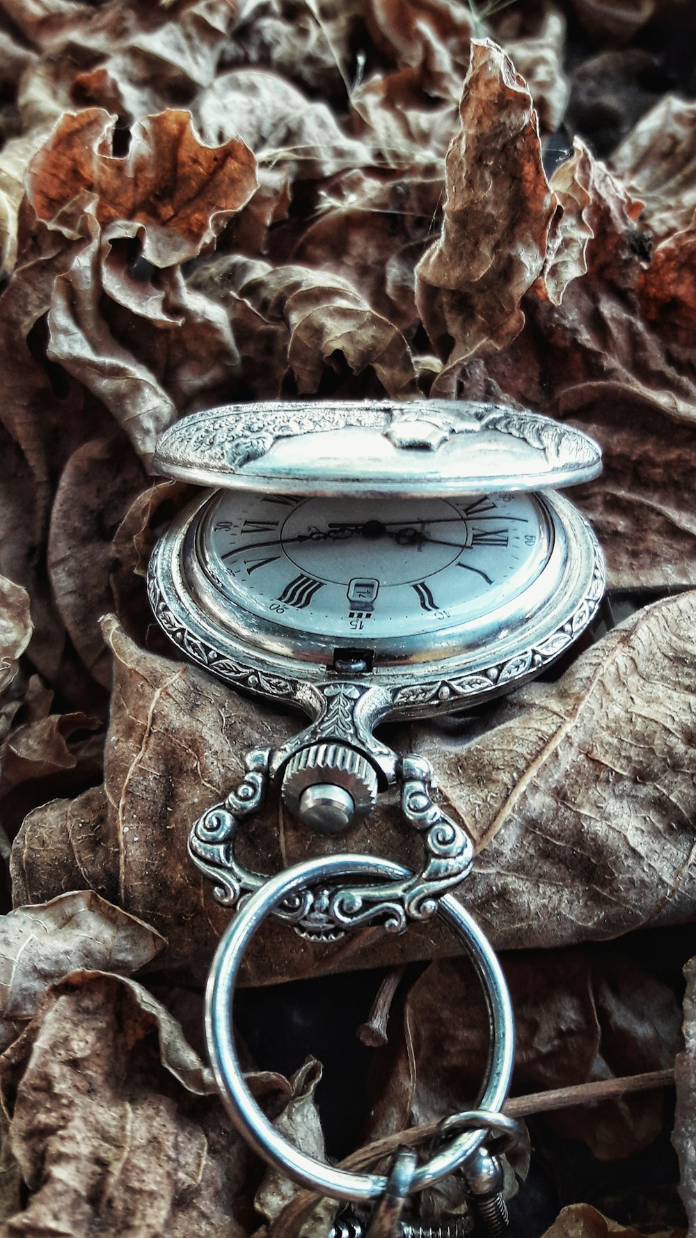 silver pocket watch on brown textile