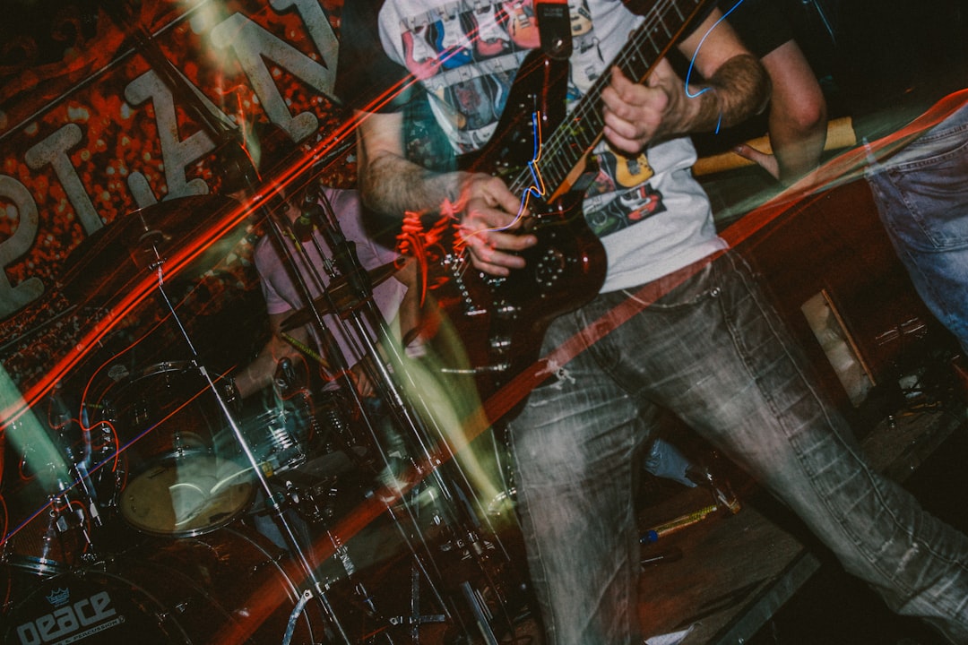 man in red and white shirt playing electric guitar