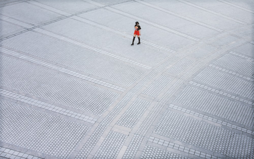 person in red jacket and black pants walking on white snow field during daytime