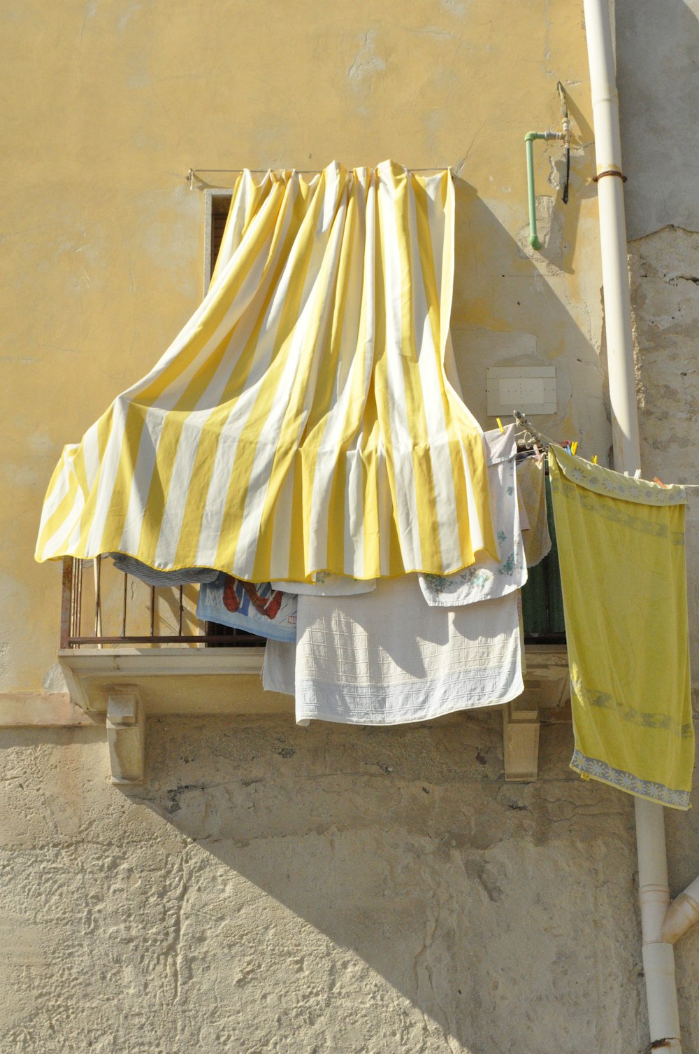 têxtil amarelo e branco na cerca de madeira marrom
