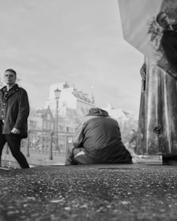 Black and white photo of a model posing in hood drip cargo pants under city lights