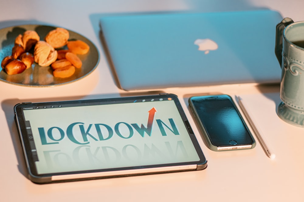青と白のiPadケースの横にあるシルバーのMacBook
