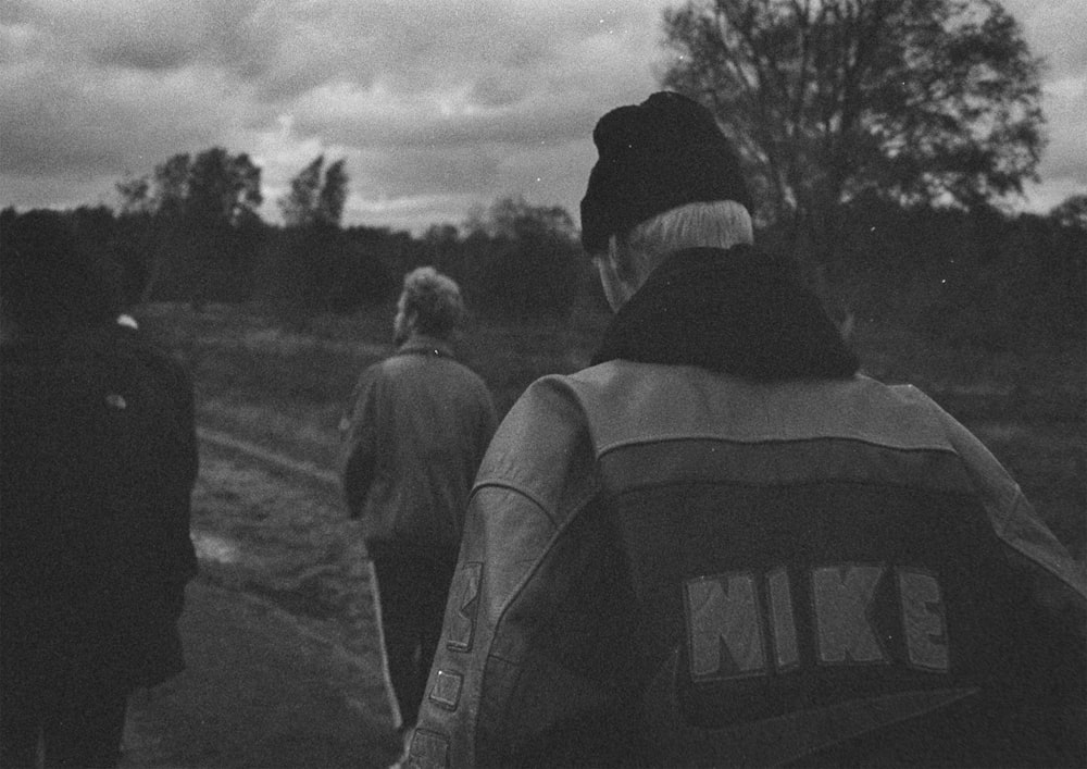 grayscale photo of people walking on field