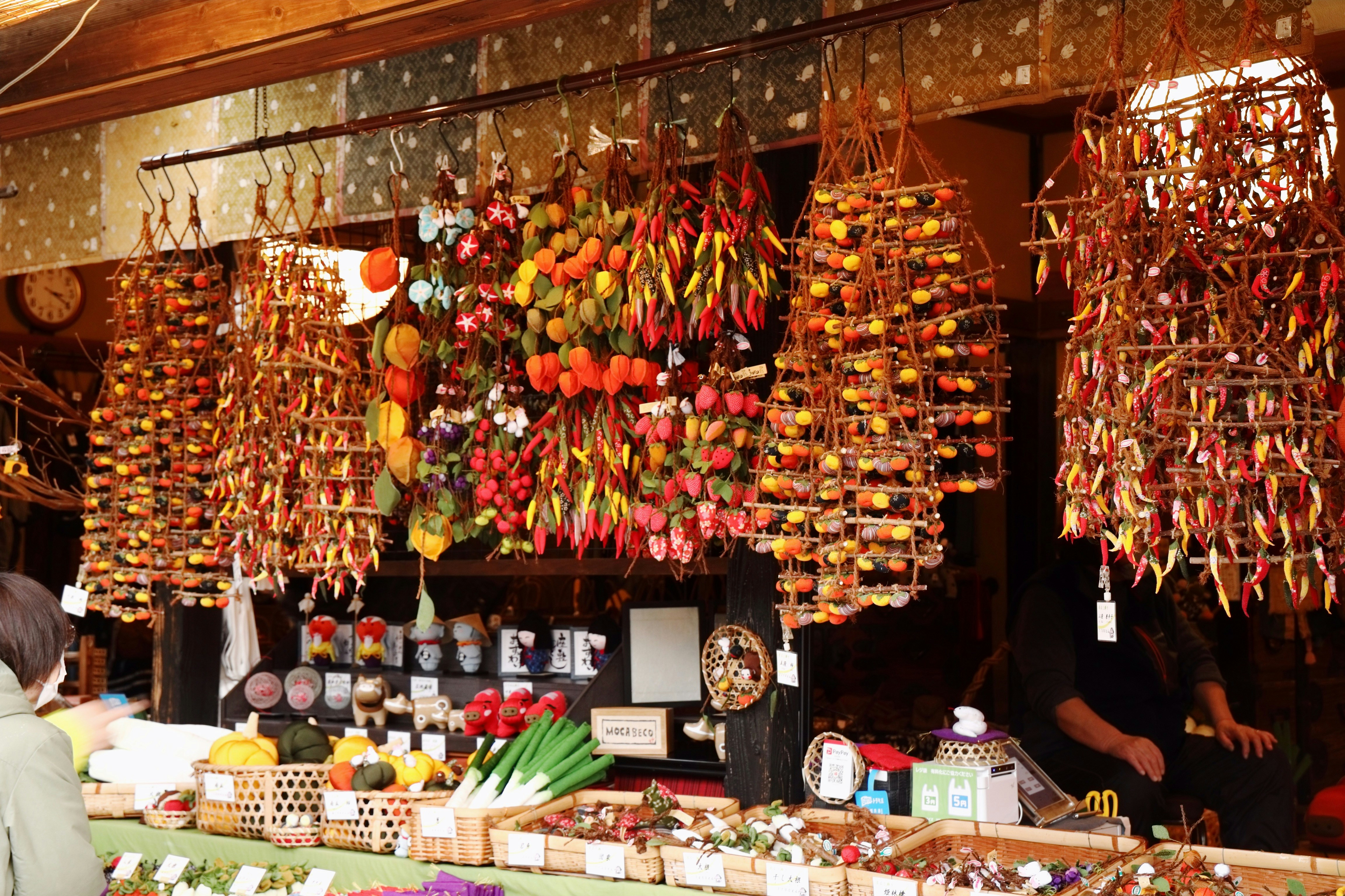 A customer inspects traditional handmade ornaments at a market stall.