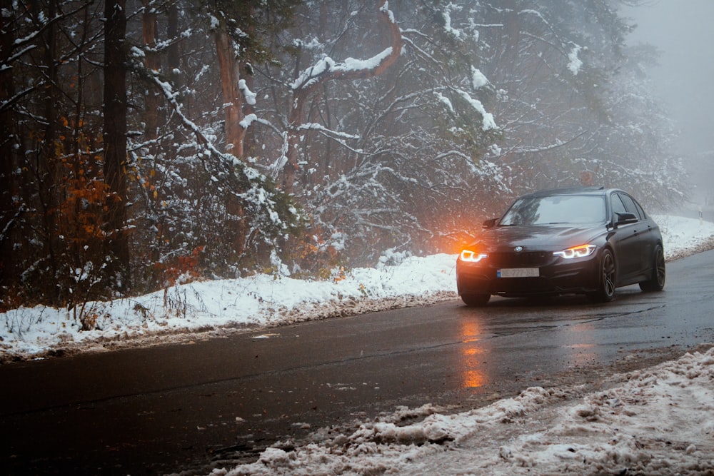 black car on road covered with snow during daytime