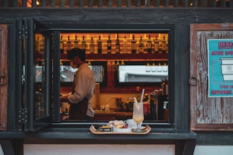 man in white dress shirt standing in front of brown wooden table