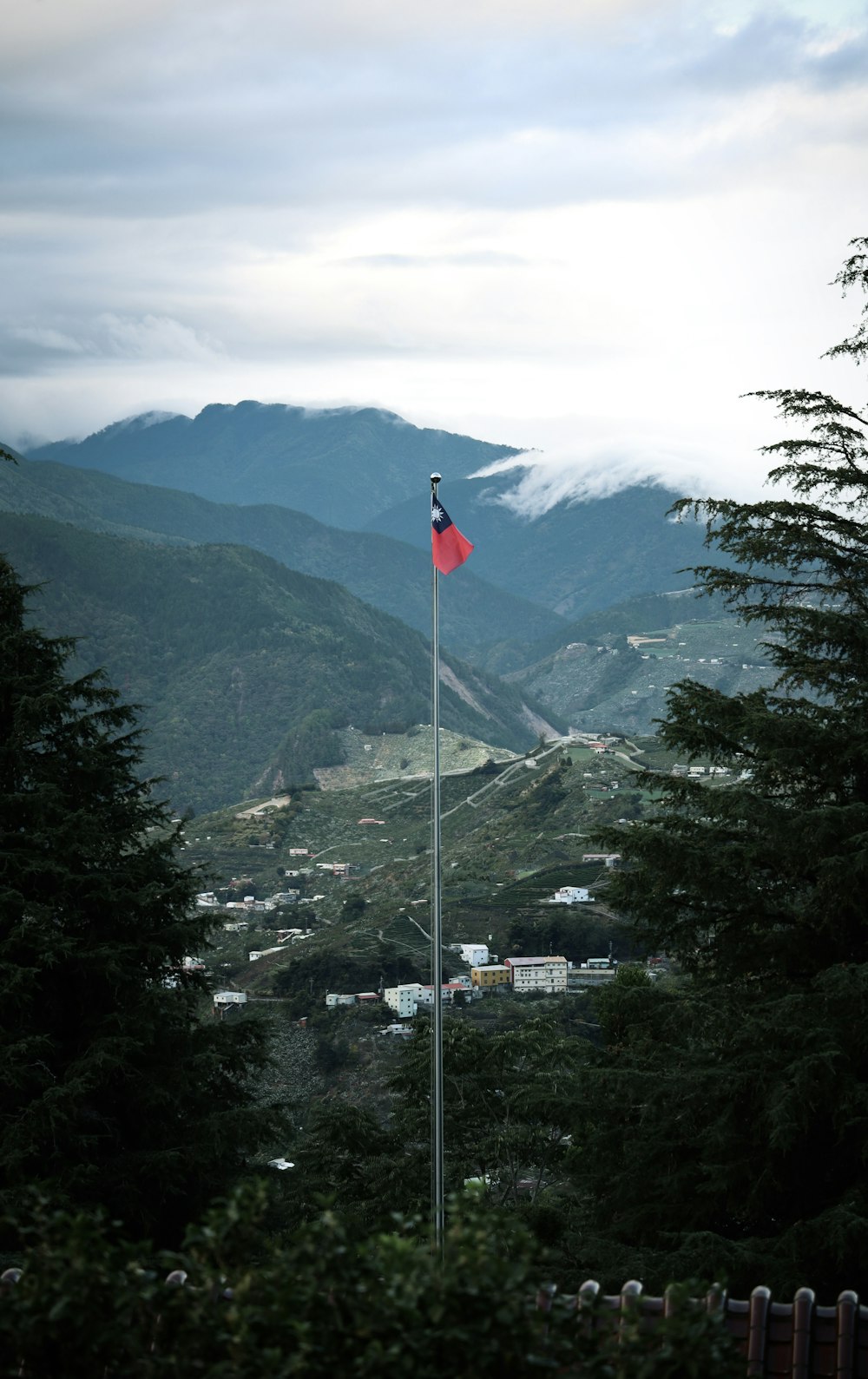Red and white flag on pole near green trees and mountains during daytime  photo – Free Grey Image on Unsplash