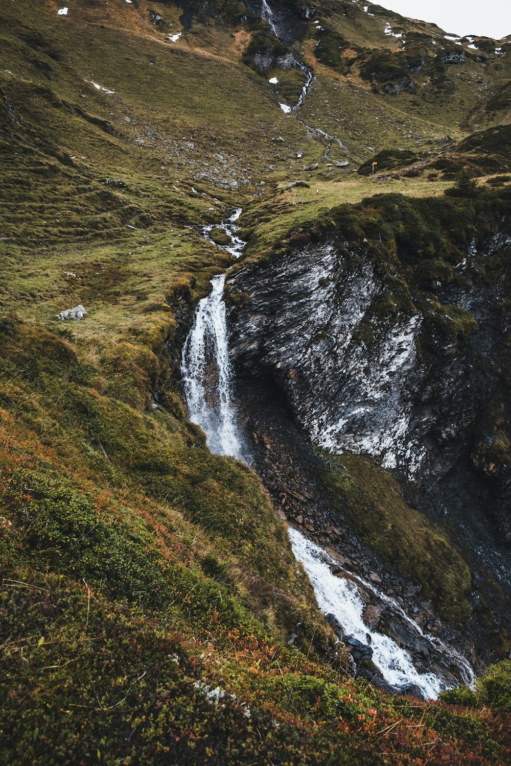 water falls on green and brown mountain