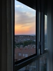 A serene view of the city skyline from a hotel room window at sunset.