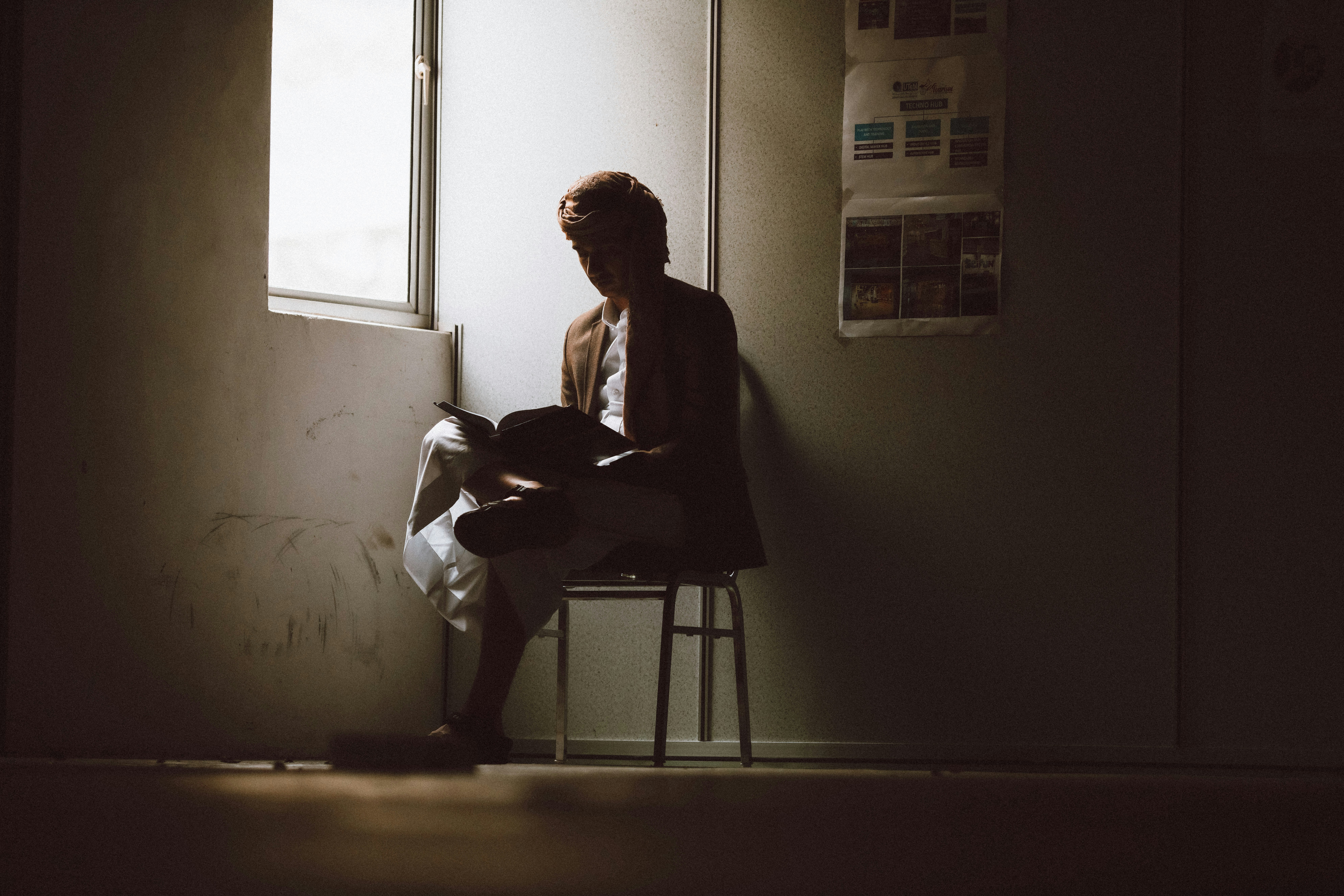 A person reading in the corner of a room. 