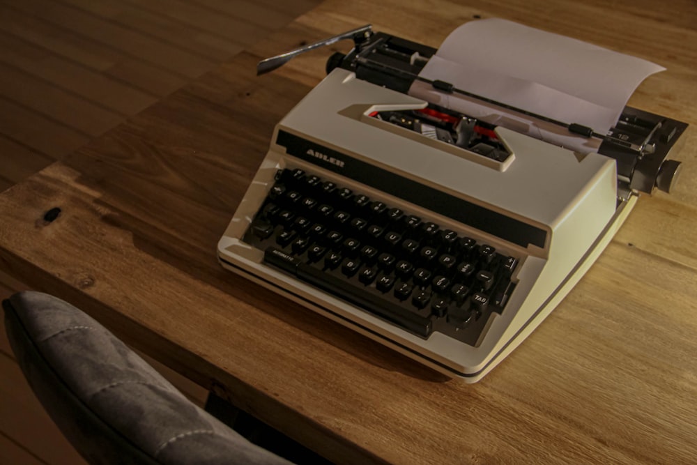 white and black typewriter on brown wooden table