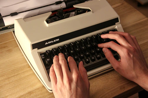 person holding gray and black typewriter