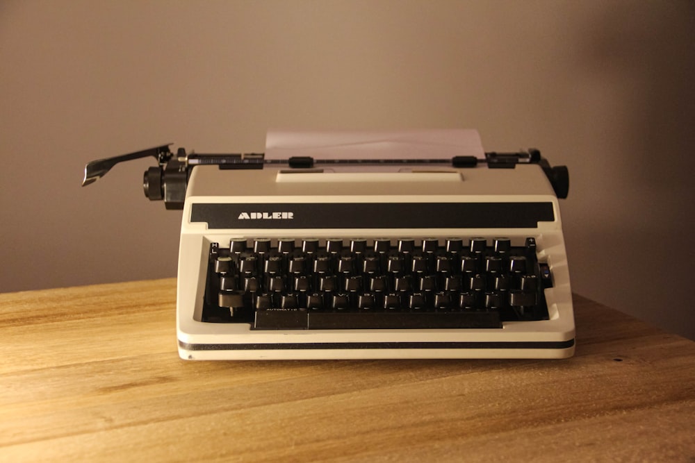 white and black typewriter on brown wooden table