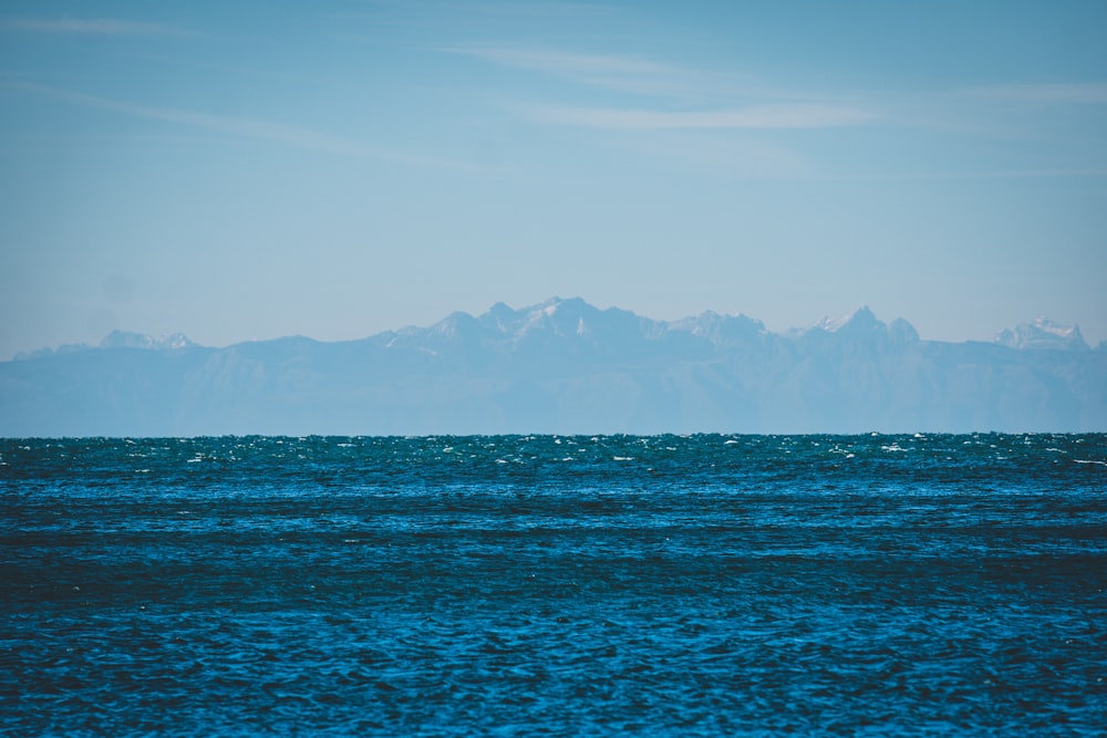 body of water near mountain during daytime