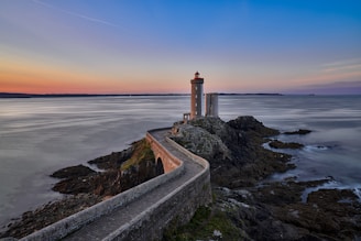 white and brown concrete lighthouse near sea during daytime