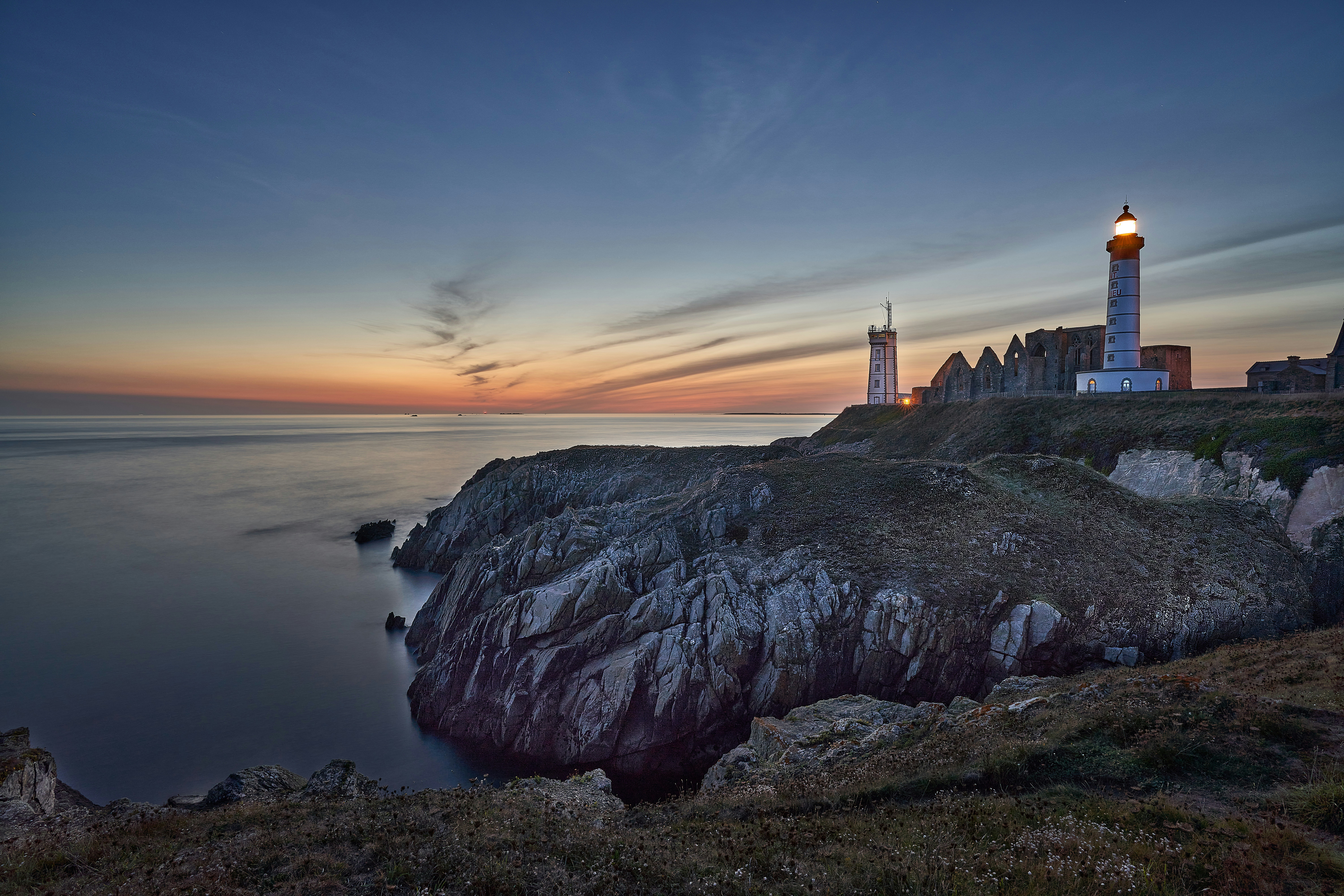 brown concrete building on top of mountain near body of water during sunset