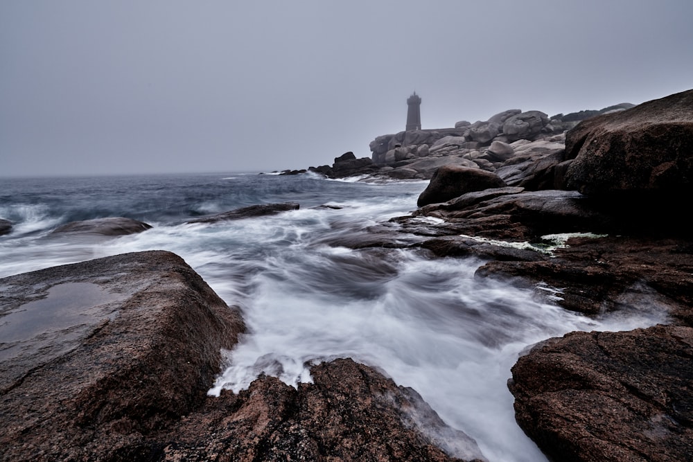 white lighthouse on brown rock formation near sea during daytime