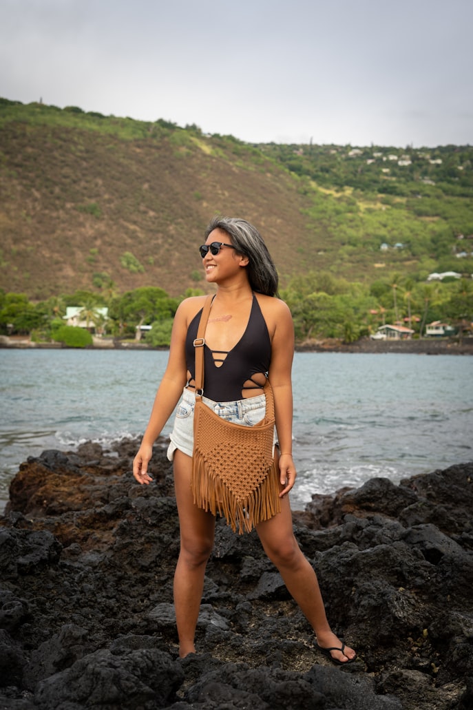 Woman in Kona Hawaii wearing a crossbody bag, denim shorts and Wolven sustainable swimsuit.