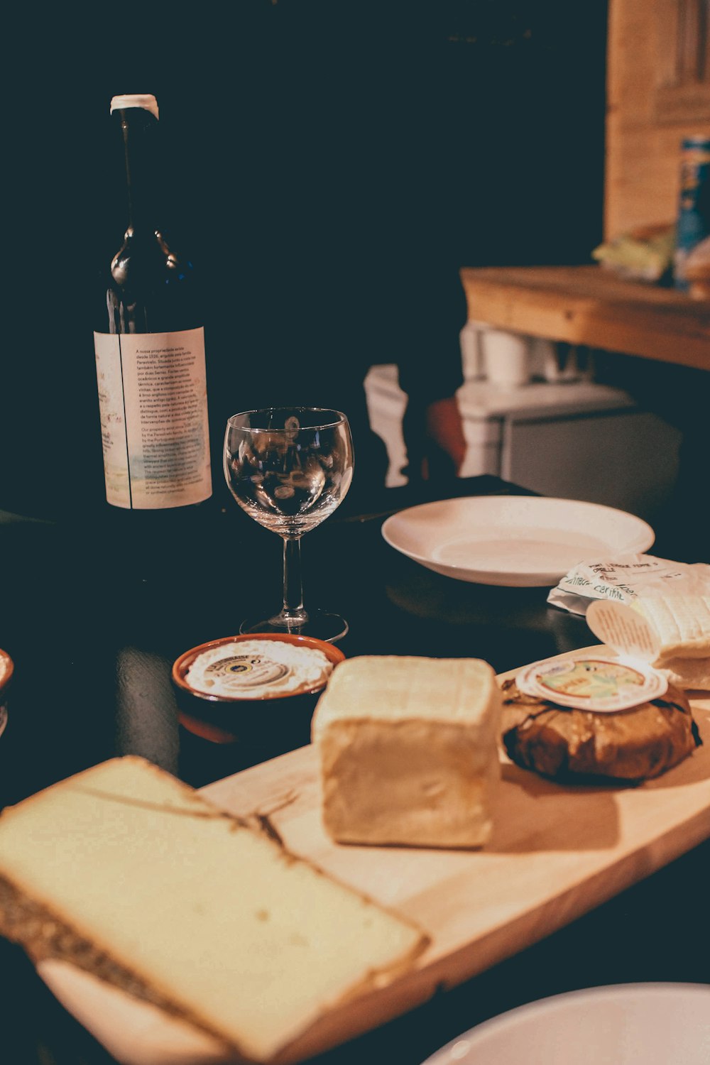 copo de vinho claro ao lado da placa de cerâmica branca na mesa preta