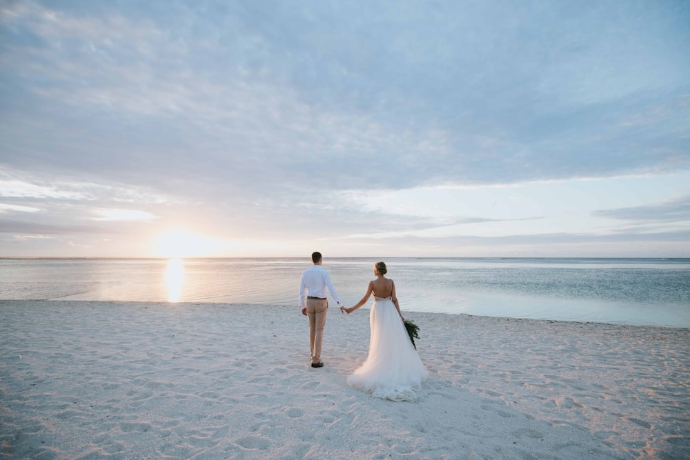 man and woman walking on beach during daytime