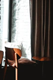 Elegant pillowcases draped over a rustic wooden chair beside a window