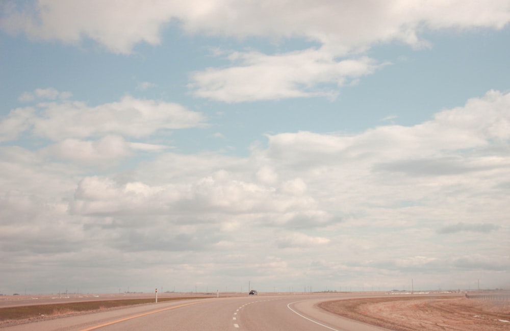 Carretera de asfalto gris bajo cielo azul y nubes blancas durante el día