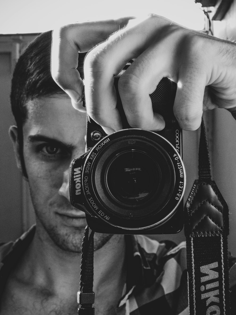 grayscale photo of man holding nikon dslr camera