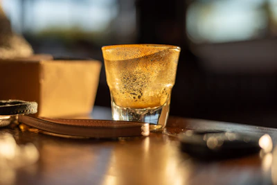 Close-up of frothy beer glasses clinking on a wooden table with sunlight streaming in