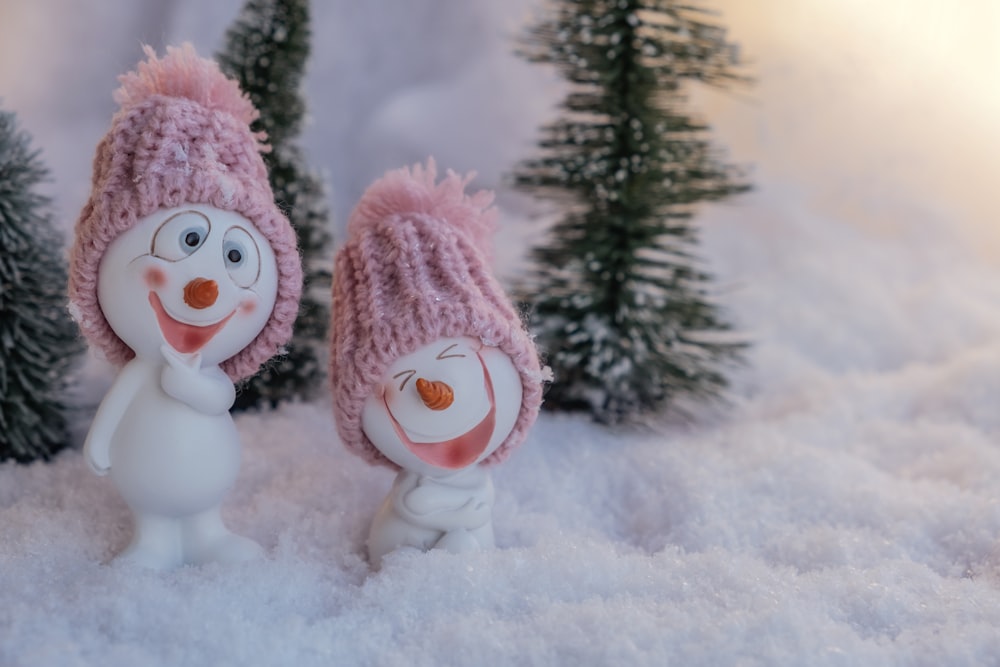 snowman with pink scarf on snow covered ground