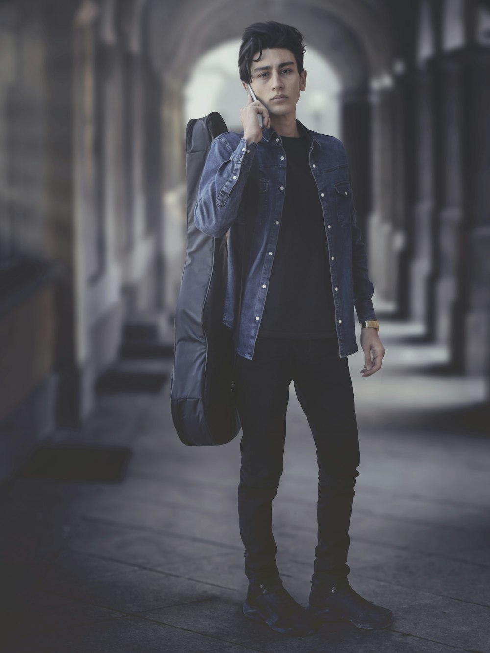 man in black leather jacket standing on sidewalk during daytime