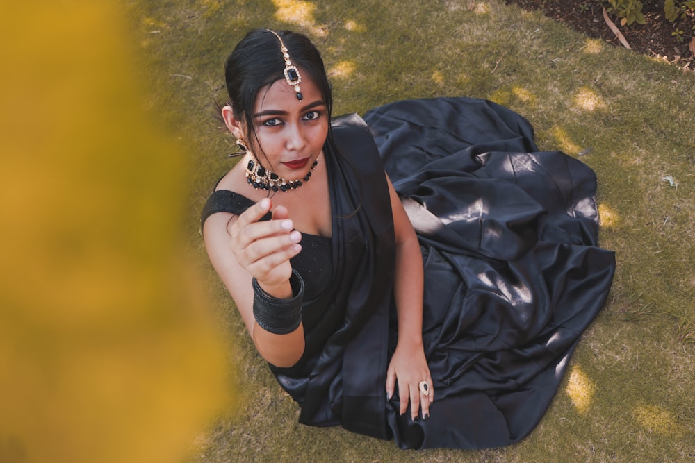 woman in black dress sitting on green grass field