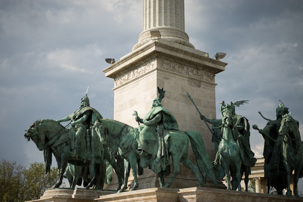 people riding horses statue under white clouds during daytime