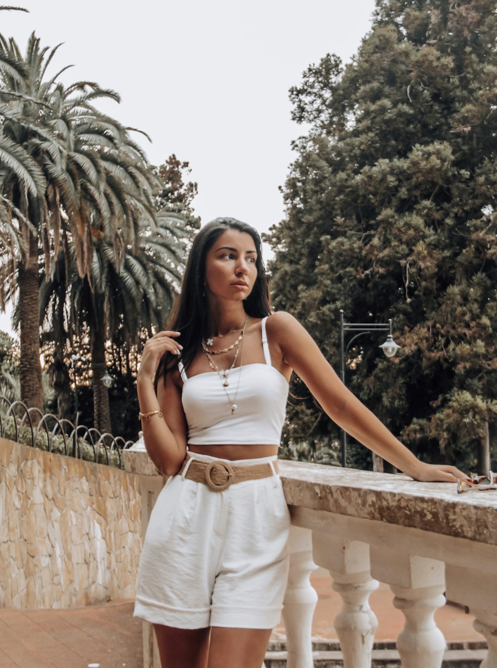 woman in white spaghetti strap dress standing near brown concrete wall during daytime