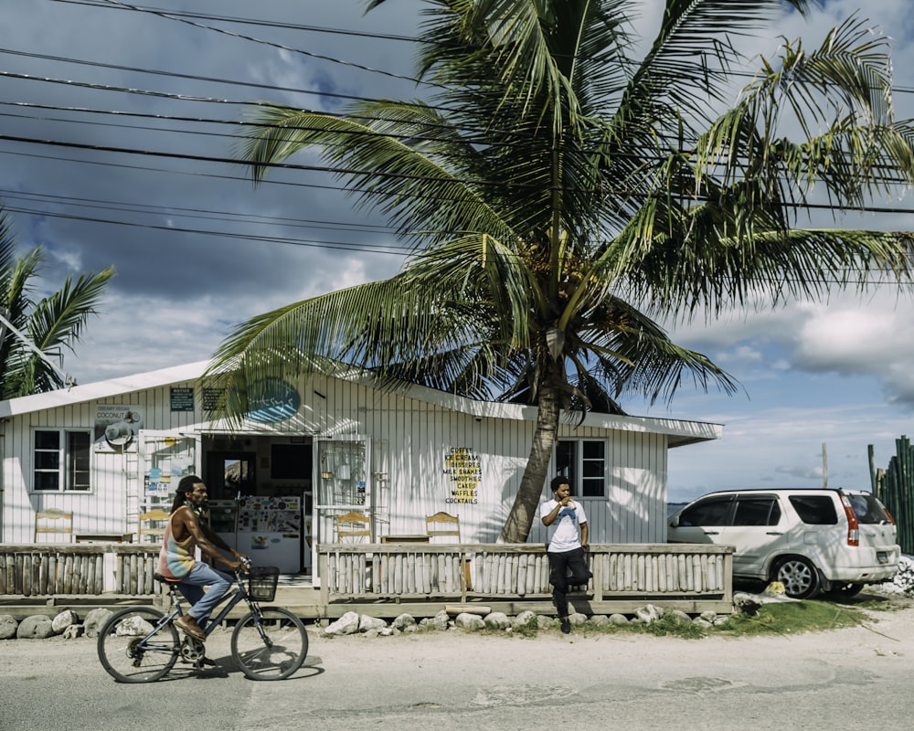 man in black shirt riding bicycle near palm tree during daytime