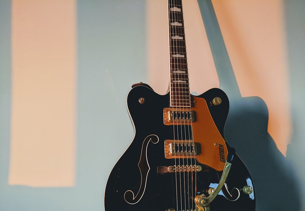 black electric guitar on white wall