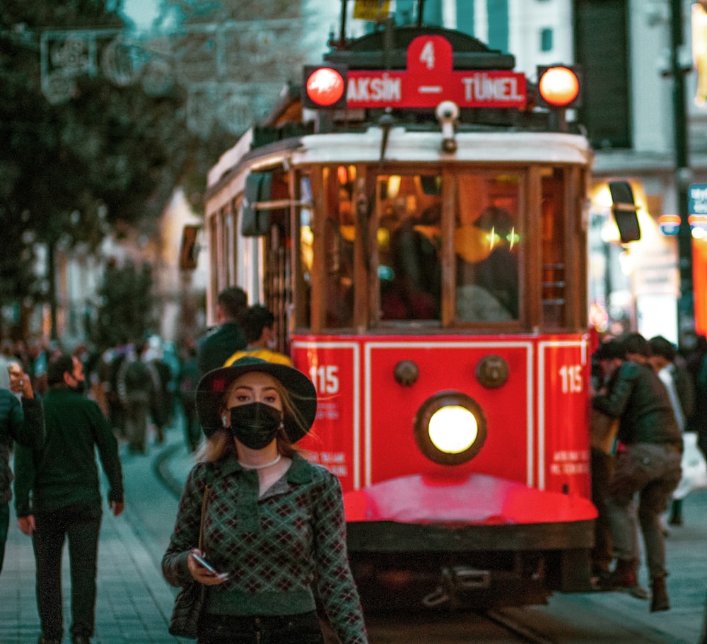 woman in black and white long sleeve shirt standing beside red tram during daytime