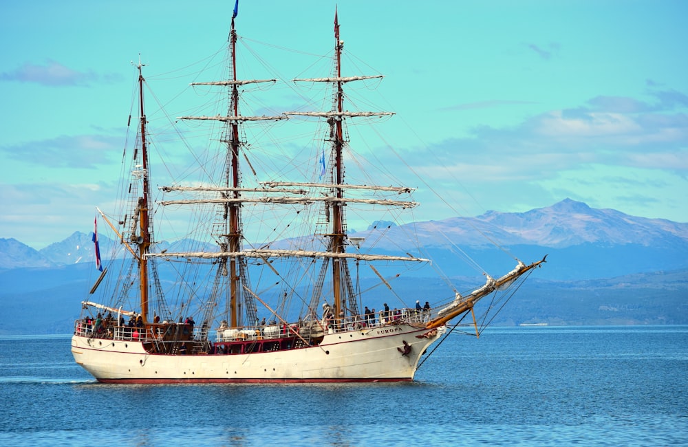 weißes und braunes Schiff auf See unter blauem Himmel tagsüber