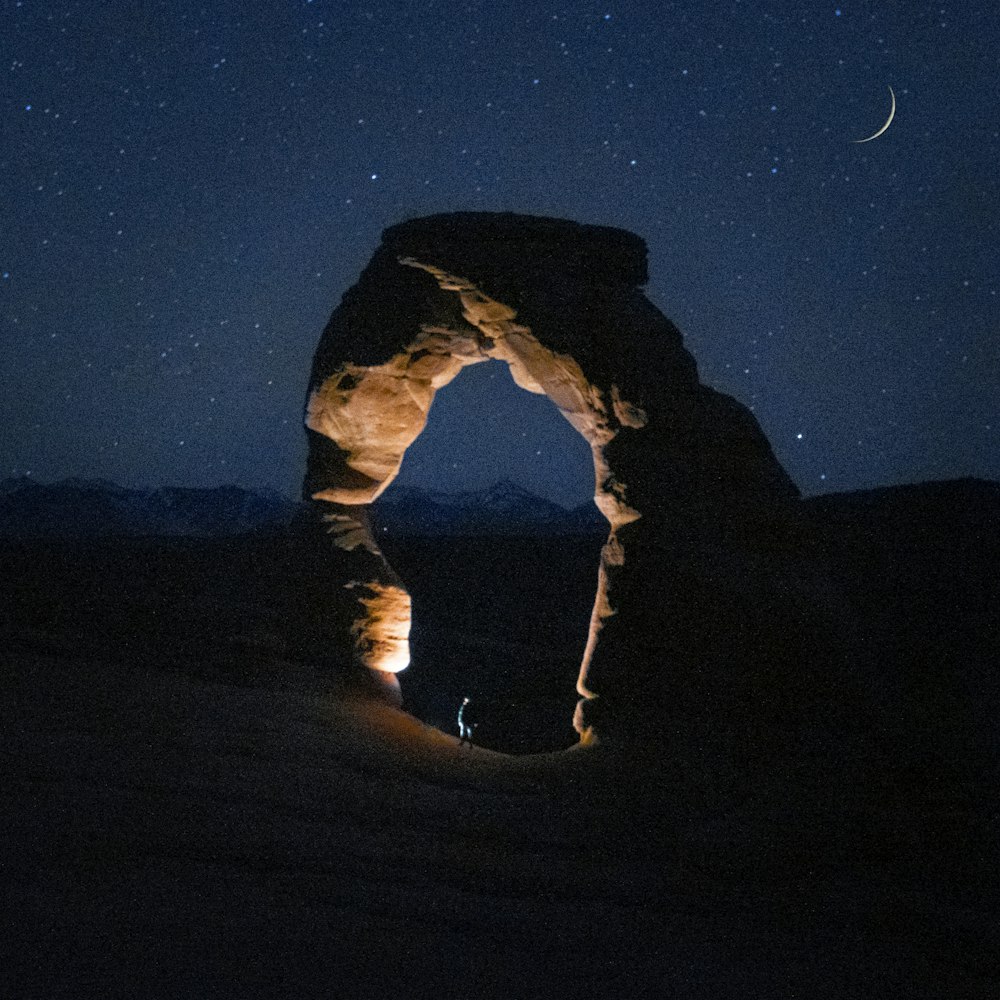 man in black jacket and pants standing on brown sand during night time