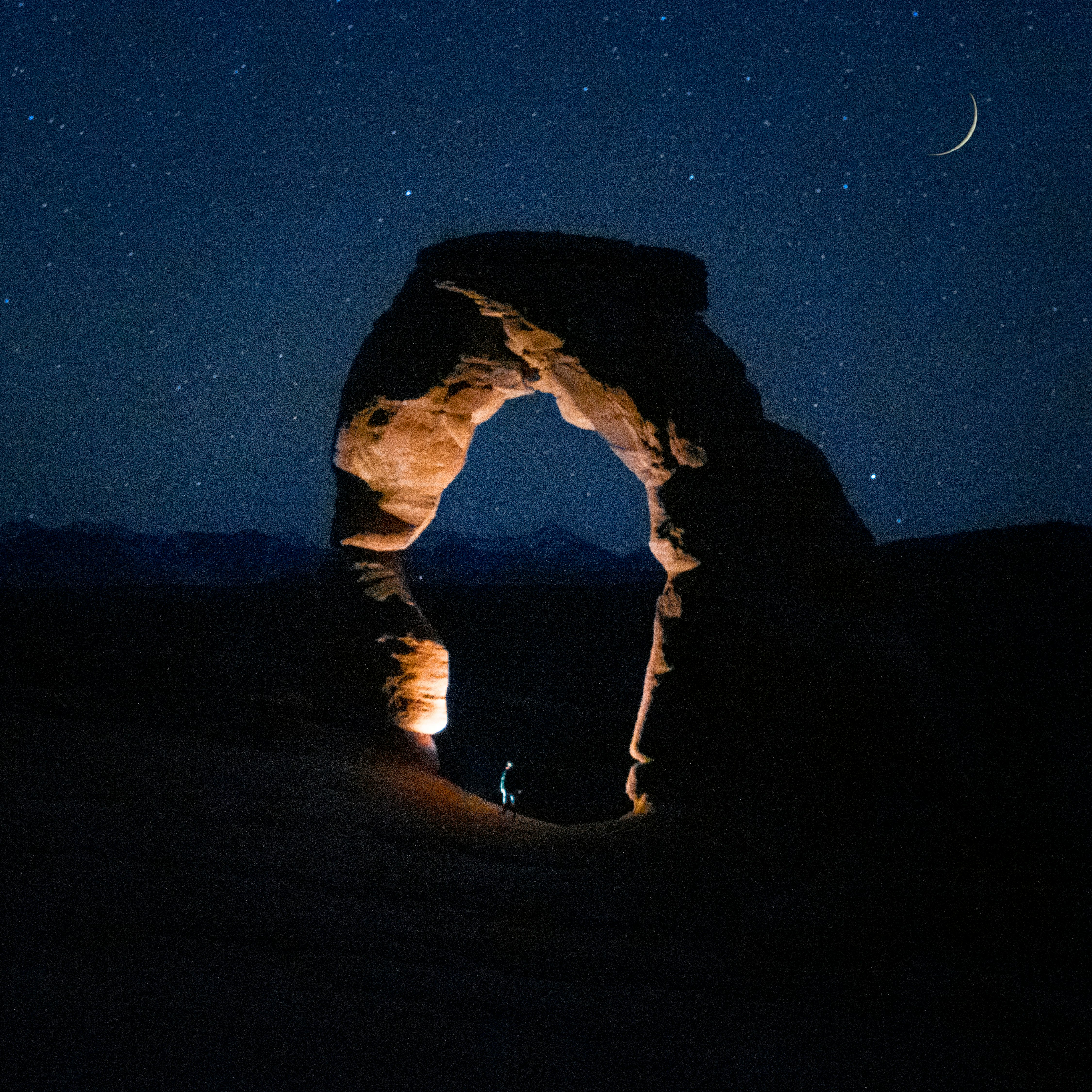 man in black jacket and pants standing on brown sand during night time