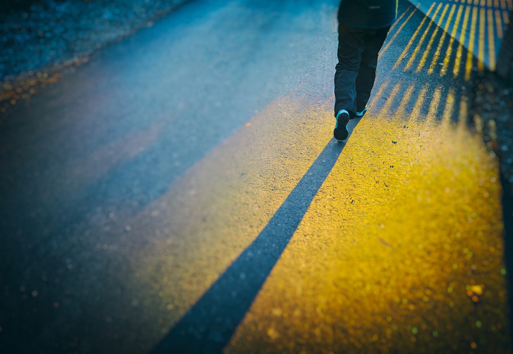 person in black pants walking on gray concrete road during daytime